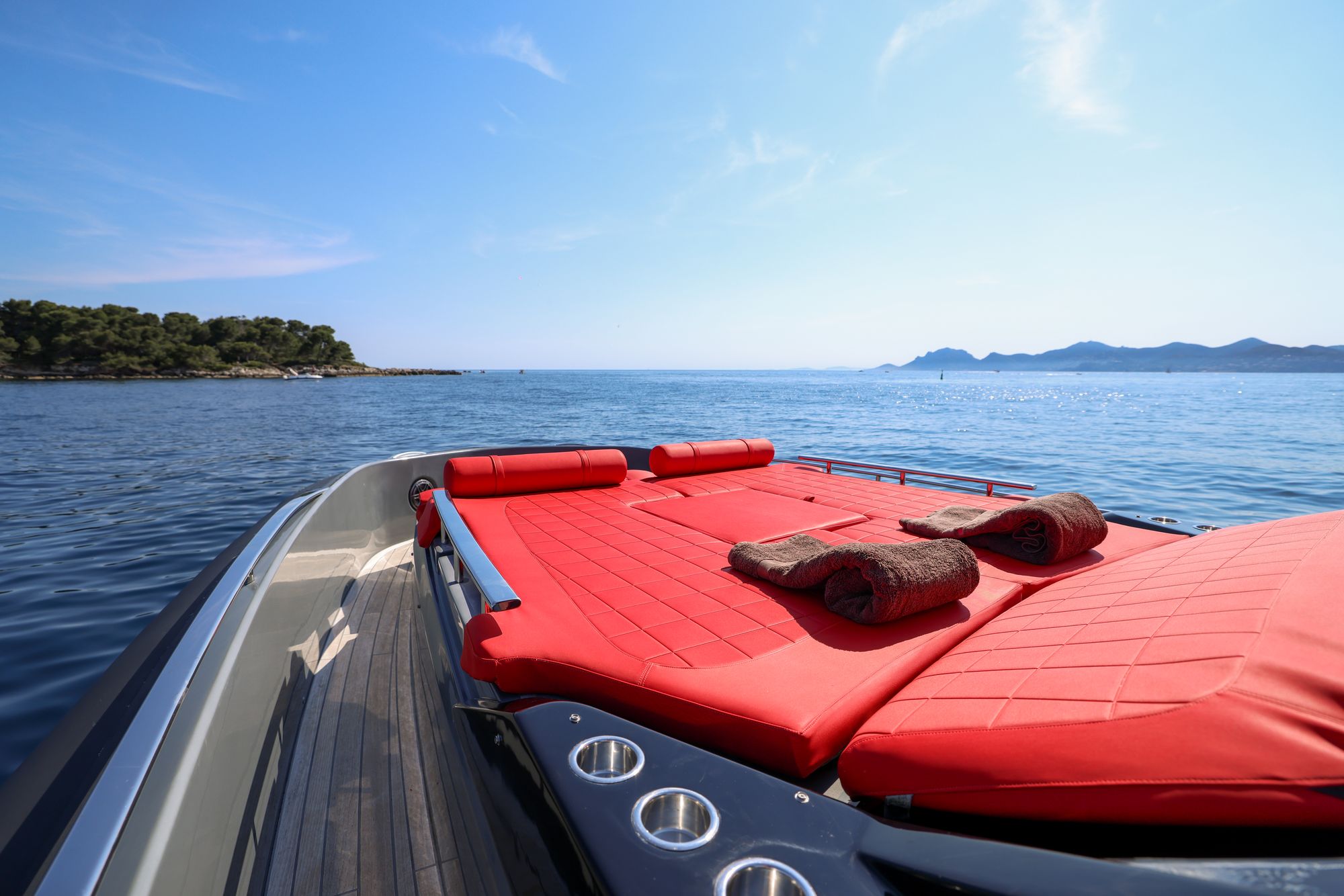Rolled towels laid out on the red bow sunbeds, a pine-covered island off the bow