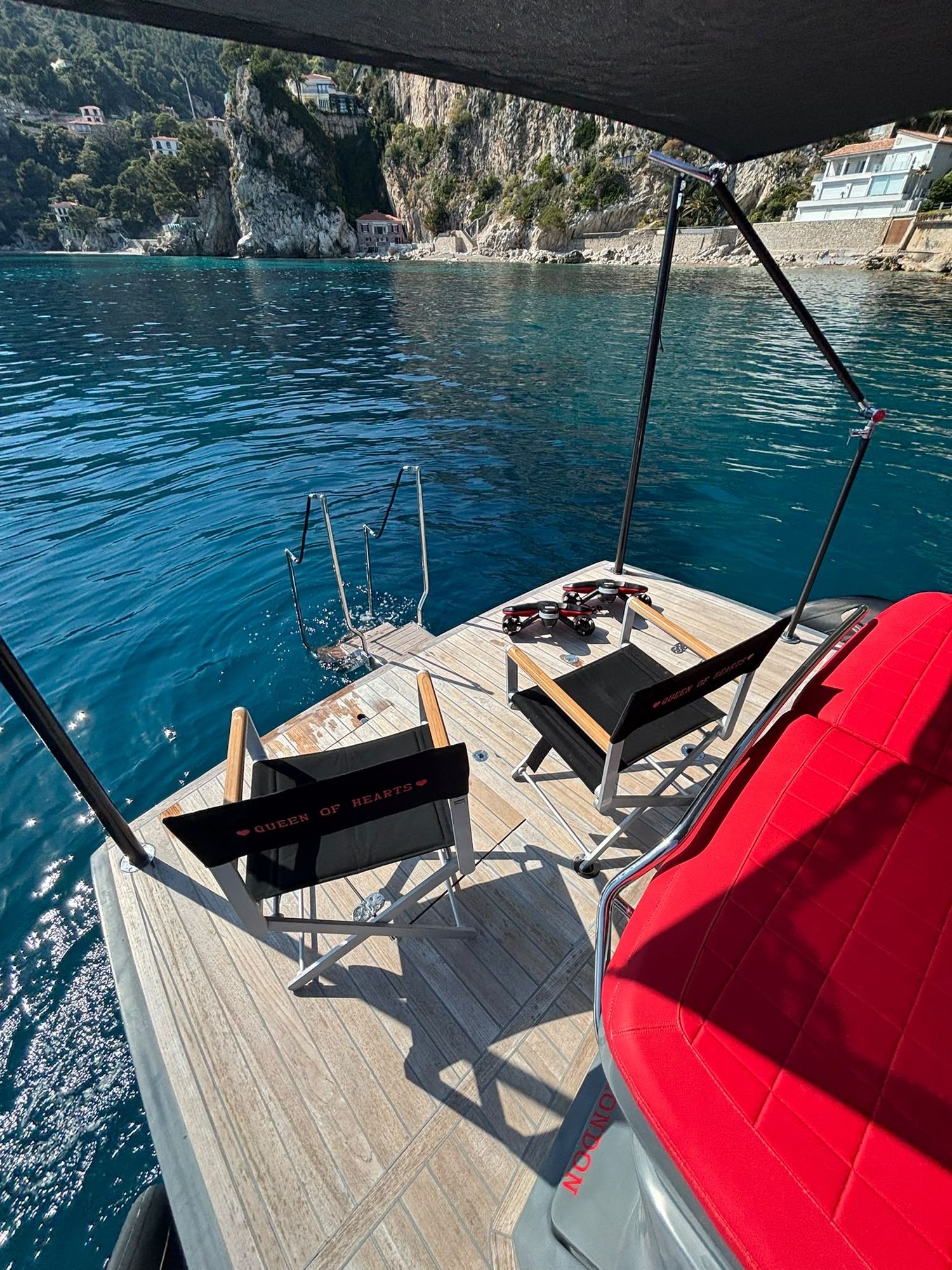 The bathing platform with the swimming ladder down into clear turquoise water, two Queen of Hearts chairs on the teak