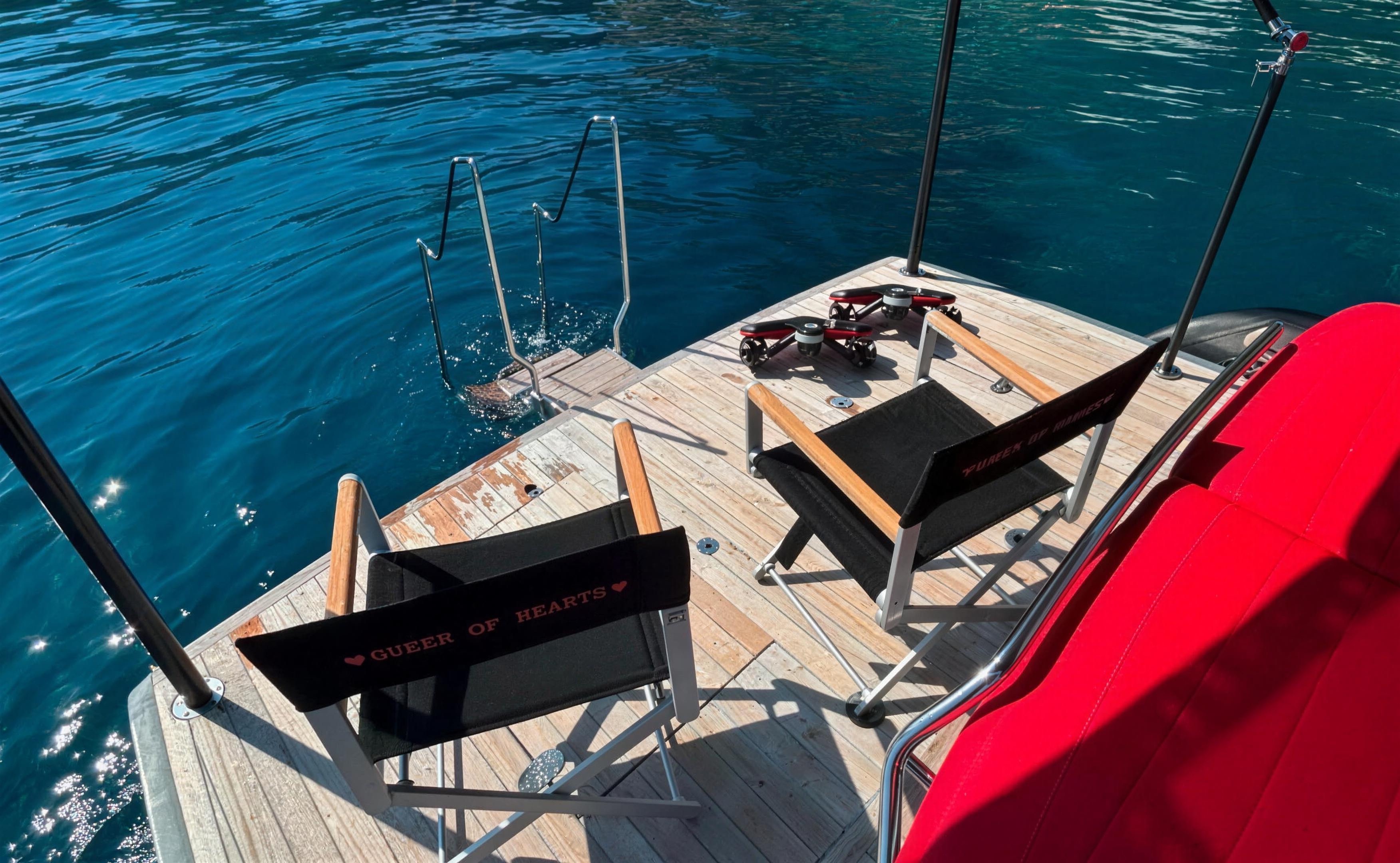 Queen of Hearts director's chairs on the swim platform over the turquoise water of the Cap