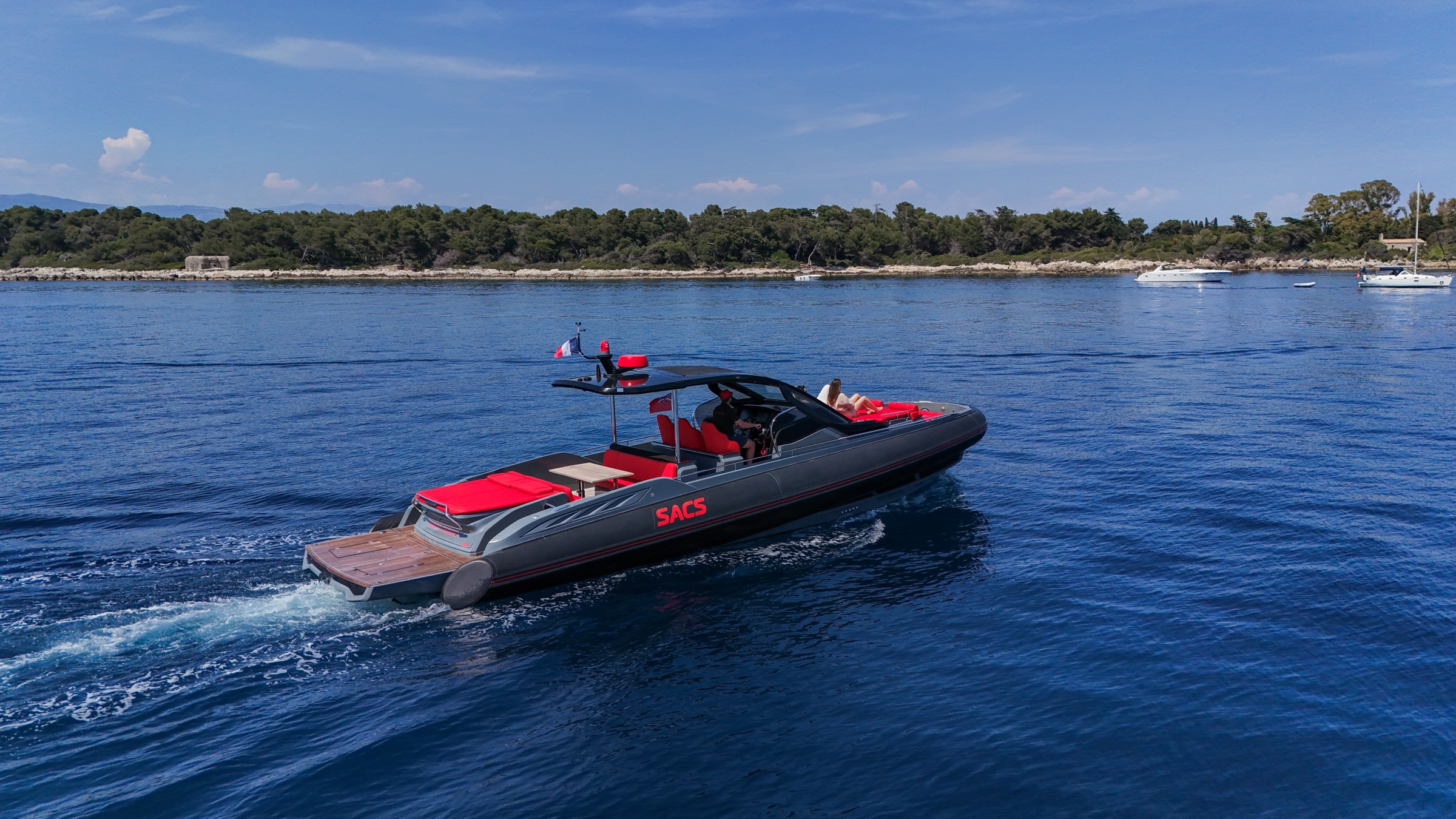 Aerial view of the Queen of Hearts, a black and red SACS Rebel 47, running along the Riviera coastline
