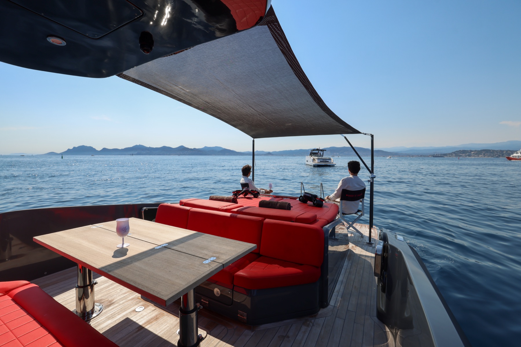 Guests under the shade sail on the aft deck, drinks in hand