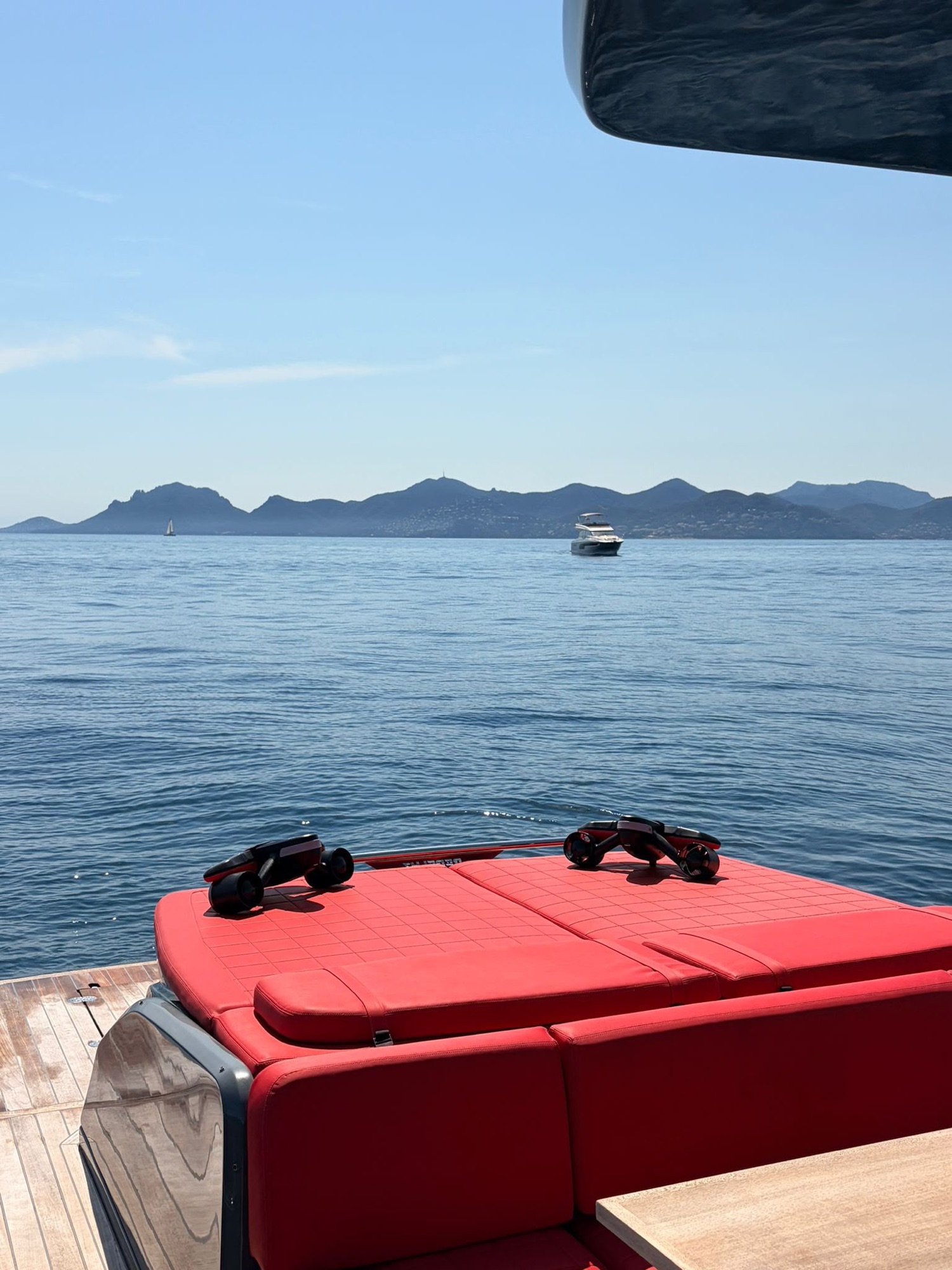 Seabobs resting on the red aft sunbed at anchor, the hills of the coast beyond