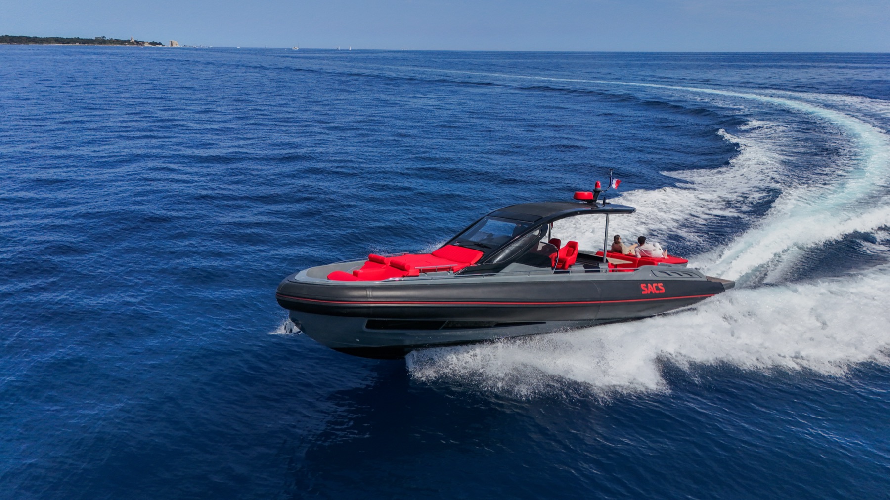 Aerial of the Queen of Hearts carving a turn on open water, her wake curving behind her