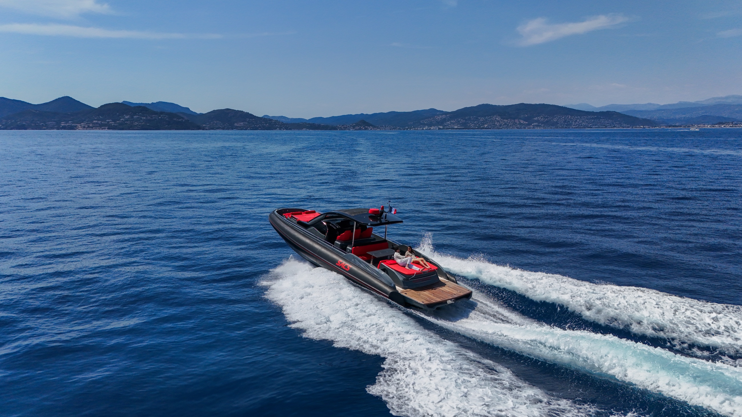 Side profile of the black and red SACS Rebel 47 moving across deep blue water
