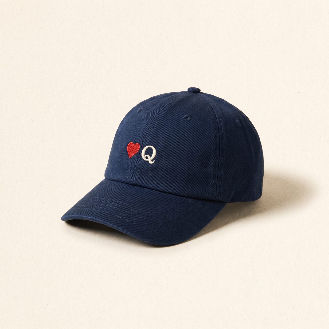 Navy cotton cap with a small embroidered red heart and cream Q
