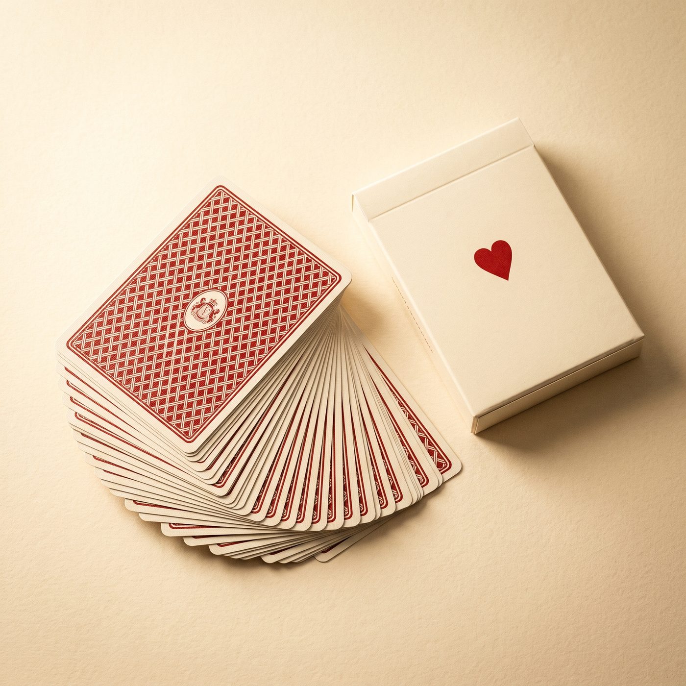 Playing cards with a red lattice back, fanned beside a cream tuck box